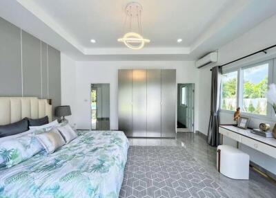 Modern bedroom with attached bathroom, wardrobe, and large windows