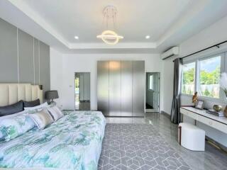 Modern bedroom with attached bathroom, wardrobe, and large windows