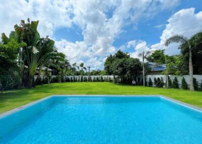 Backyard with swimming pool and lush green lawn