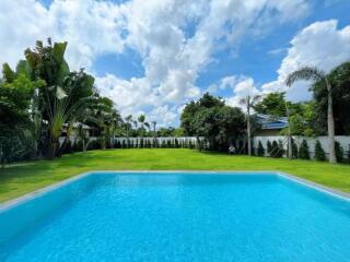 Backyard with swimming pool and lush green lawn