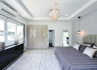 Modern airy bedroom with large window, stylish lighting, and ample storage.