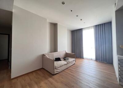 Minimalist living room with a sofa, hardwood floor, and large window with curtains