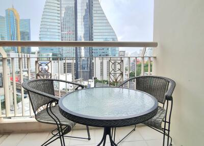 Outdoor balcony area with a round glass table and two chairs