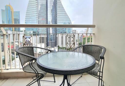 Outdoor balcony area with a round glass table and two chairs