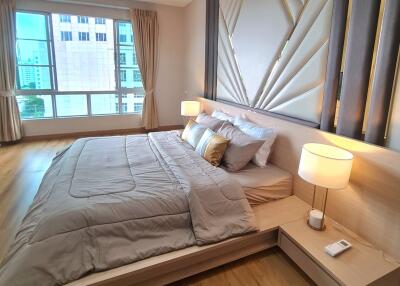 Spacious bedroom with large window, comfortable bed, modern furnishings, and bedside lamps