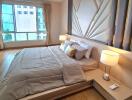 Spacious bedroom with large window, comfortable bed, modern furnishings, and bedside lamps