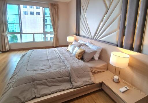 Spacious bedroom with large window, comfortable bed, modern furnishings, and bedside lamps