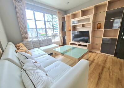 Modern living room with large window, white sofa, glass coffee table, and entertainment center