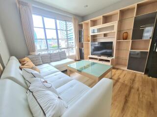 Modern living room with large window, white sofa, glass coffee table, and entertainment center