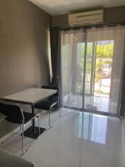 Small dining area with a table and two chairs next to a glass door leading outside