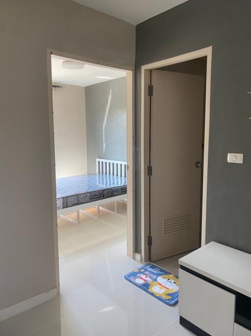 View into a bedroom from an adjacent room, showing a bed and part of a nightstand.