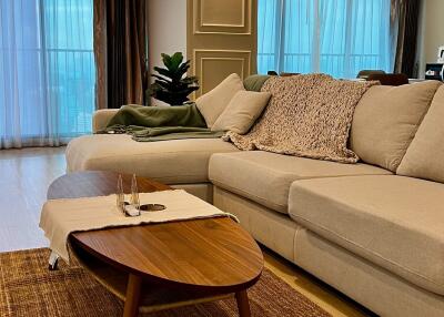 Modern living room with beige sectional sofa, wooden coffee table, and large windows