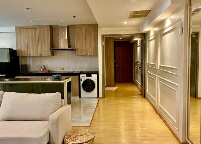 Modern open-plan living room and kitchen with beige sofa and integrated appliances.