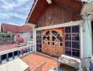 Area outside house with large decorative wooden doors and tiled patio