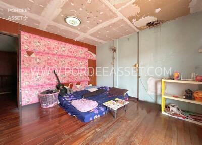 A bedroom under renovation with a ceiling showing damage, a mattress on the floor, and a disorganized layout