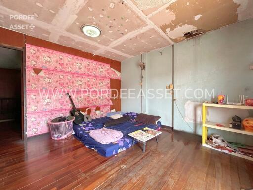 A bedroom under renovation with a ceiling showing damage, a mattress on the floor, and a disorganized layout