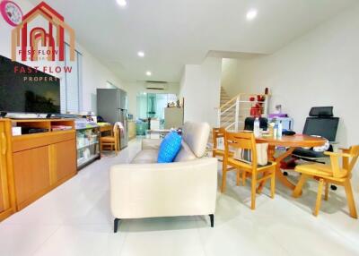 Modern living area with beige sofa, wooden dining table, and open staircase