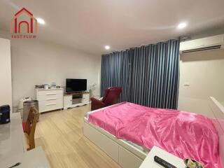 Modern bedroom with wooden floor, pink bed cover, TV, desk, air conditioning, and closed curtains