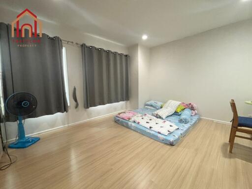 Minimalist bedroom with floor mattress and fan