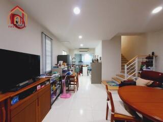 Modern living area with TV, dining set, and staircase