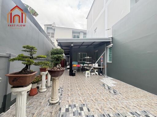 Spacious tiled outdoor area with seating, plants, and a covered section