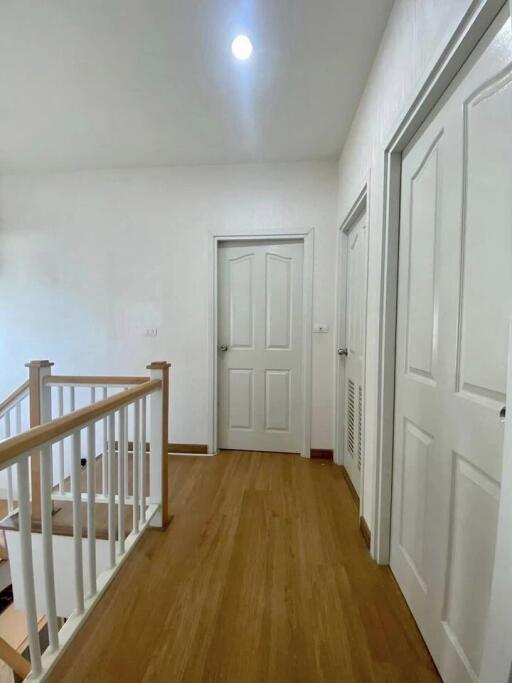 Spacious hallway with wooden flooring and multiple doors