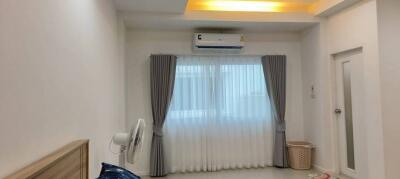 Well-lit bedroom with air conditioning and window with curtains