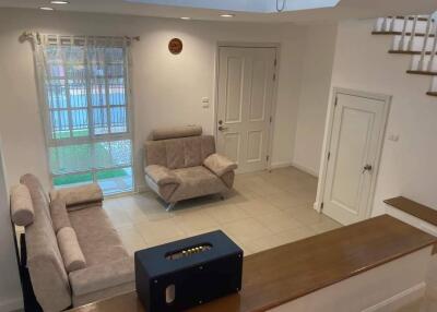 Cozy living room with two beige sofas, door, and windows