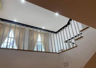 Staircase with railings leading to the upper floor, featuring windows with curtains