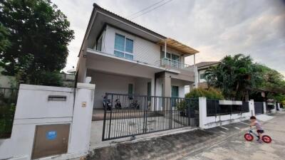 Exterior view of a modern two-story house with a child riding a bike in the foreground