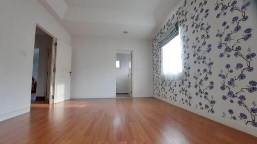 Spacious living room with wooden flooring and floral wallpaper