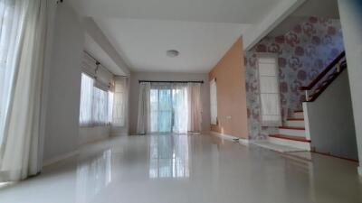 Spacious living room with large windows and staircase