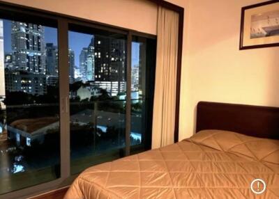 Night-time view of bedroom with large window overlooking cityscape