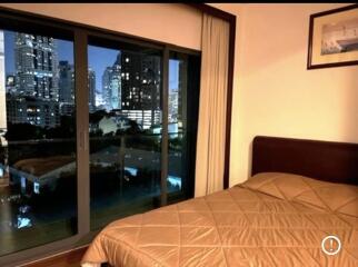 Night-time view of bedroom with large window overlooking cityscape