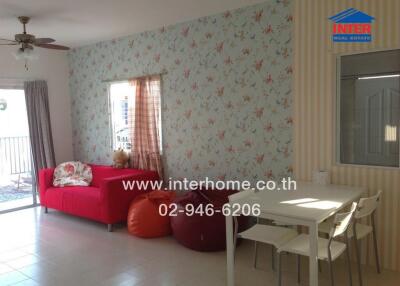 Spacious and bright living area with a red couch, dining table, and patterned wallpaper.