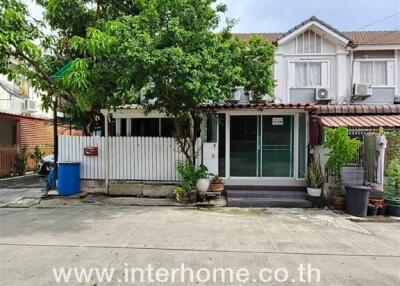 Front view of a townhouse with a small garden and driveway