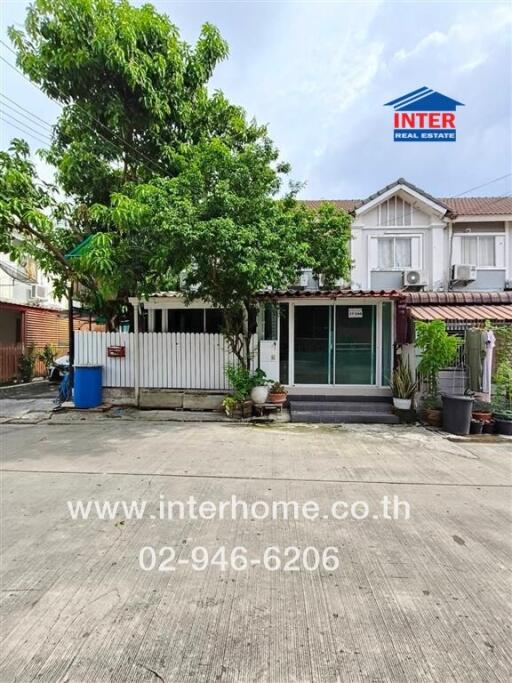 Front view of a townhouse with a small garden and driveway