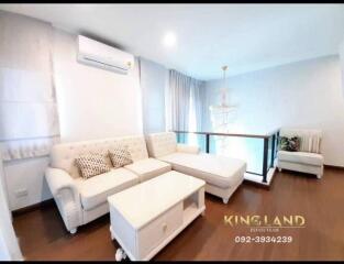 well-lit living room with white furniture and wooden floor