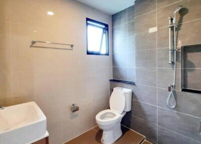 Modern bathroom with tiled walls, a toilet, a sink, and a window