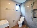 Modern bathroom with tiled walls, a toilet, a sink, and a window