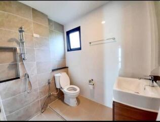 Modern bathroom with shower, toilet, sink, and window