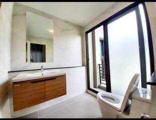 Modern bathroom with a large mirror, sink, and toilet