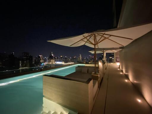 Rooftop pool with seating and city view at night