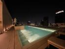 Night view of a lit rooftop pool with city skyline in the background