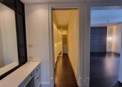 bright hallway with open doors leading to multiple rooms with cabinetry and dark flooring