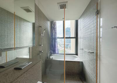 Modern bathroom with a bathtub and shower featuring city views through a large window