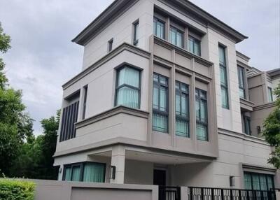 Modern three-story residential building with large windows and fenced yard