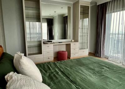 Modern bedroom with green bedding, large mirrored wardrobe, and balcony access