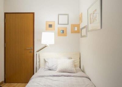 Small bedroom with a single bed, wooden door, and wall decorations