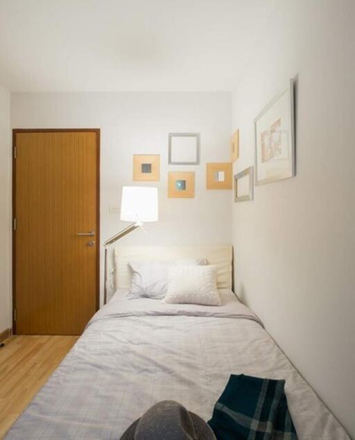 Small bedroom with a single bed, wooden door, and wall decorations